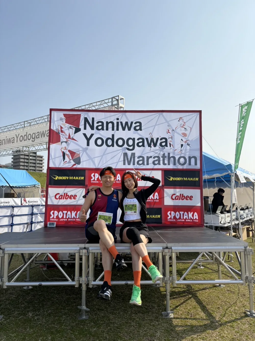 なにわ淀川ハーフマラソンの会場で並んで座るCoffee&Miles運営者の吉輝と百香