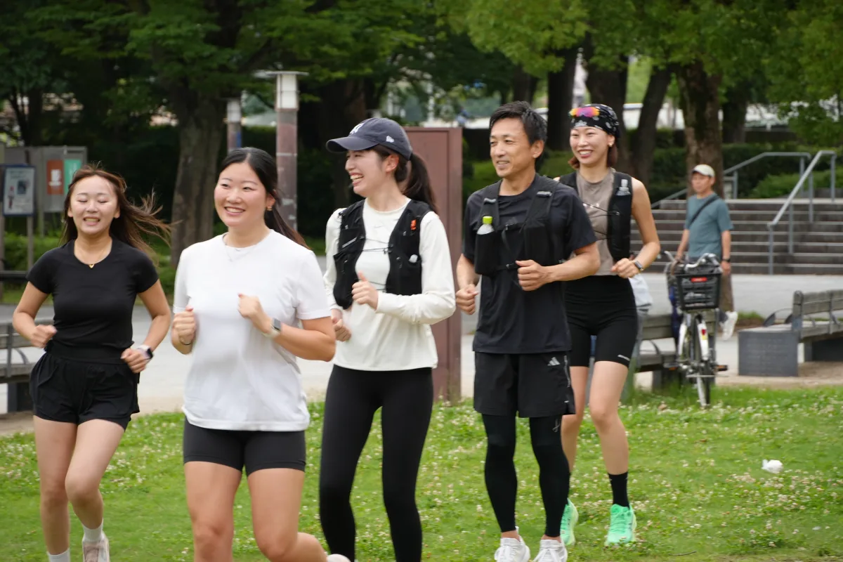 大阪城公園の芝生を笑顔で一緒に走る幅広い年代のCoffee&Miles参加者