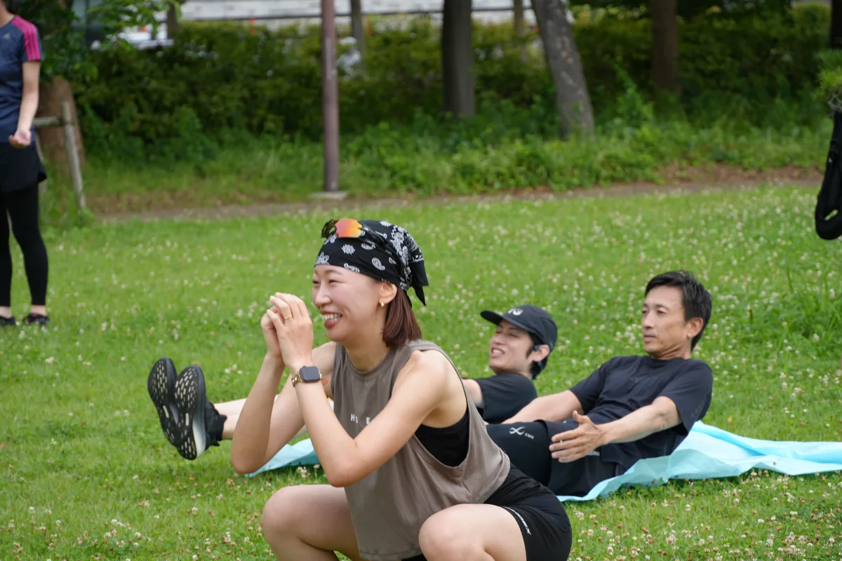 大阪城公園の芝生で笑顔を見せながらワークアウトに取り組むCoffee&Milesの参加者